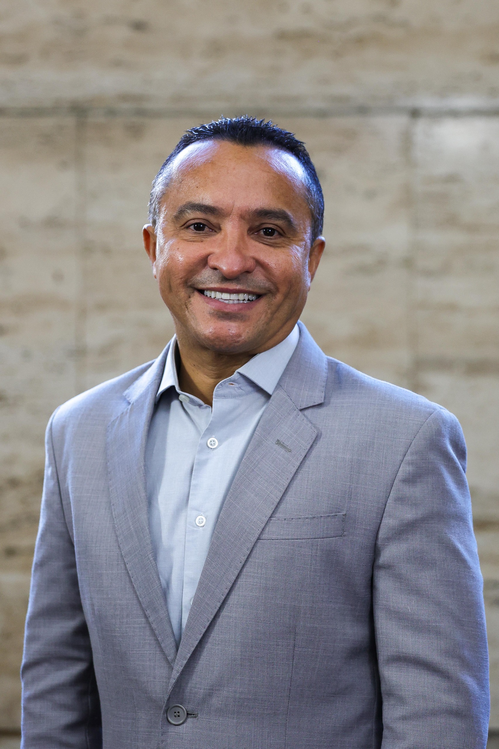 Secretário Sidney Cruz vestindo uma camisa social azul claro e terno cinza.